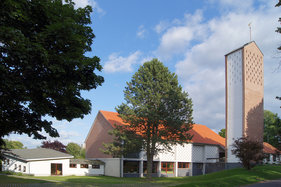 Außenansicht der Auferstehungskirche mit umliegenden Bäumen und Wiese