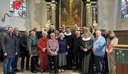 Eine Gruppe Menschen steht in einer Kirche vor dem Altarbild.