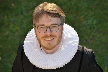 Portraitbild Pastor Arne Kutsche - Er trägt ein Talar und lächelt nach oben in die Kamera - Copyright: Ev.-Luth. Auferstehungs-Kirchengemeinde in Lübeck