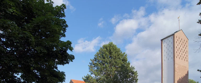 Außenansicht der Auferstehungskirche mit umliegenden Bäumen und Wiese