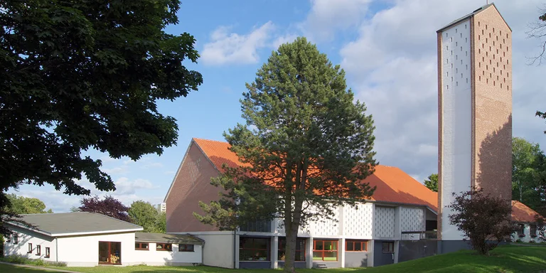 Außenansicht der Auferstehungskirche mit umliegenden Bäumen und Wiese