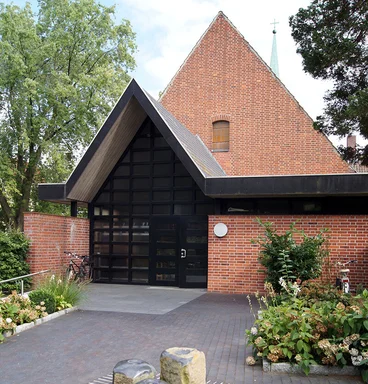 neuer Haupteingang mit Spitzgiebel neben Flachdach, davor quadratischer Brunnen           